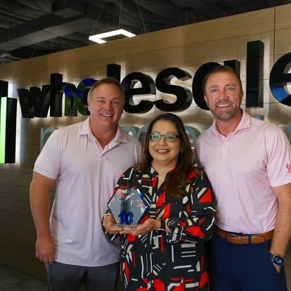 Rep receiving an award with two leaders in front of the Wholesale Payments sign at HQ